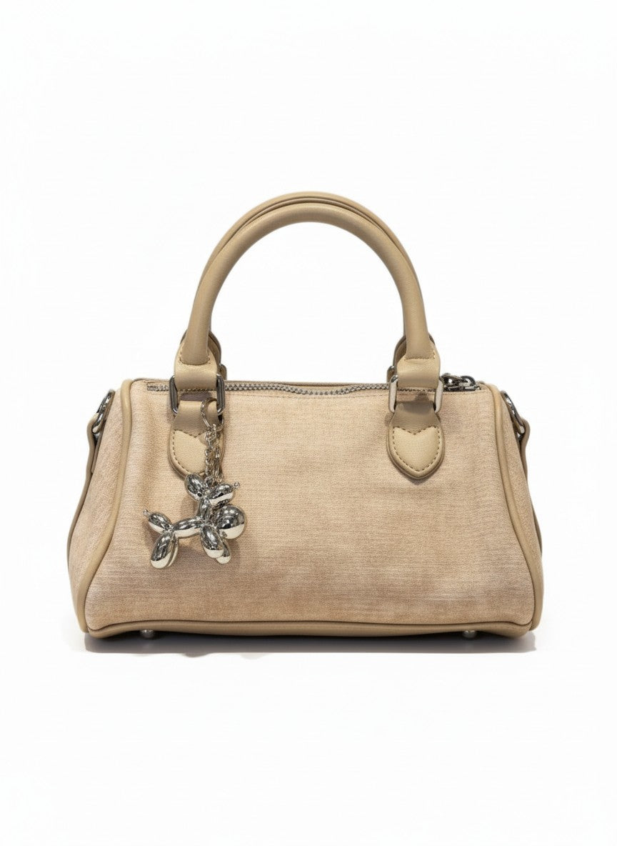 Bolso cruzado beige en sintético mate con herrajes plata y charm colgante, colección MALTA de DALALI