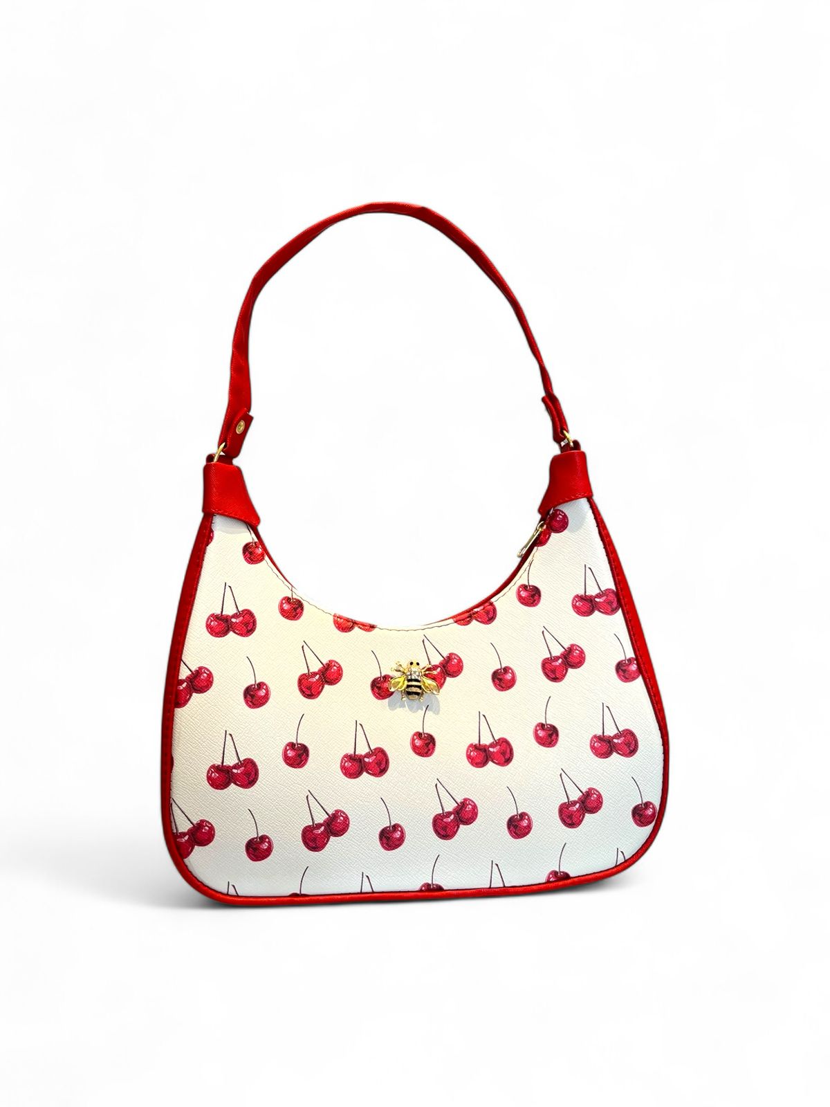 Bolsa tipo hobo con estampado de cerezas, fondo blanco, ribete rojo y herraje dorado con forma de abeja